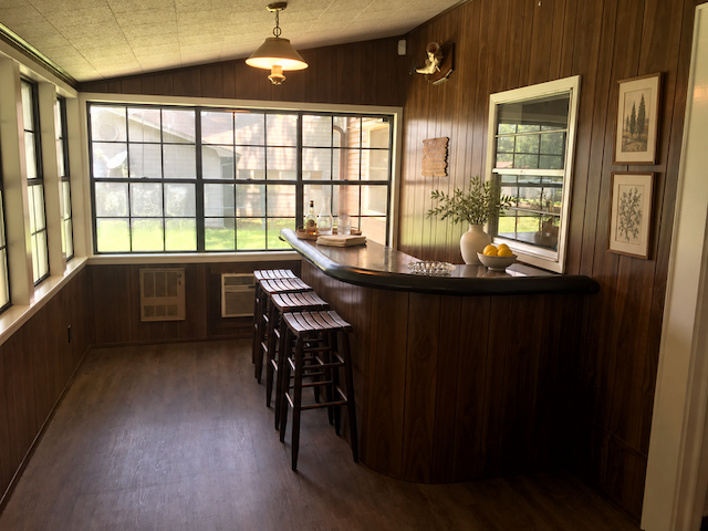 Curved wood bar with stools in the light-filled sunroom